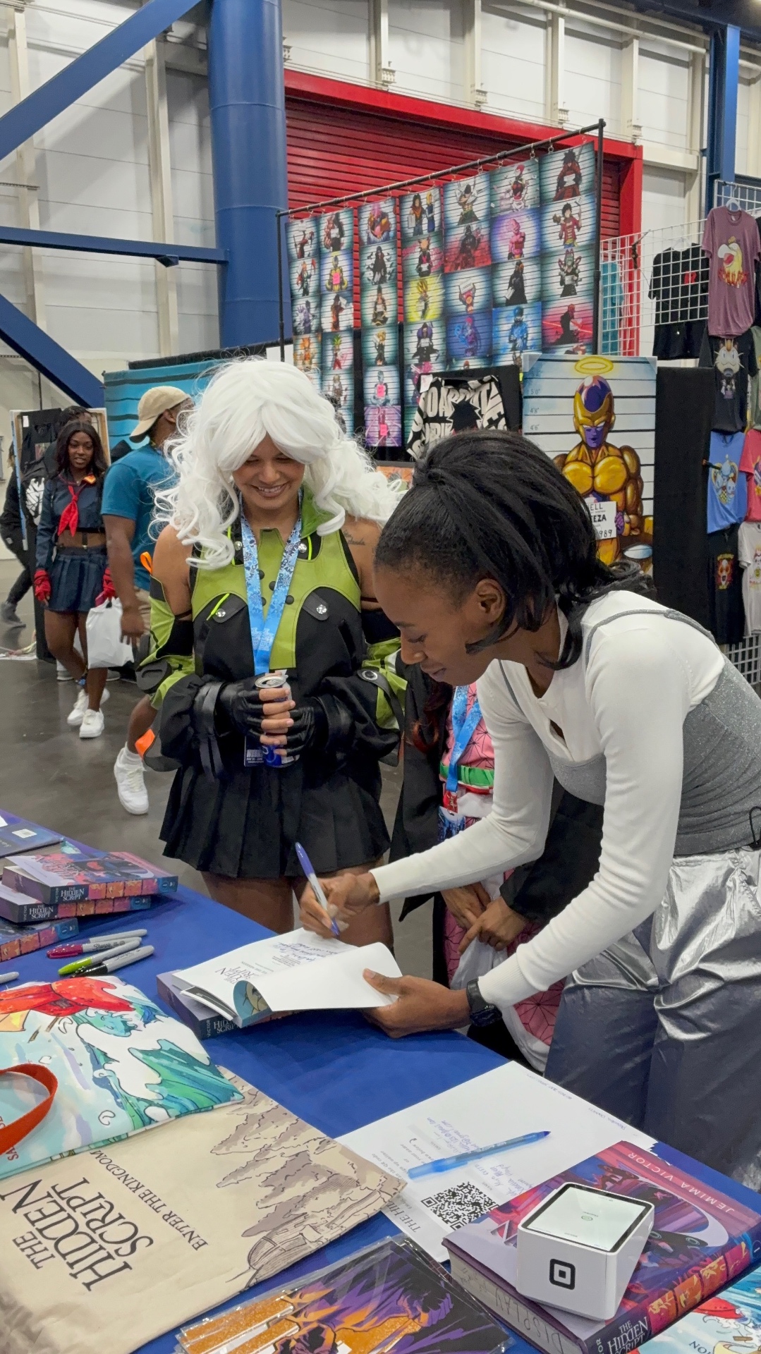 Jemima Victor signing copies of The Hidden Script at a convention booth